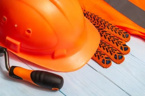 Master builder's orange protective equipment stacked on blue boards before wo Stock Photos