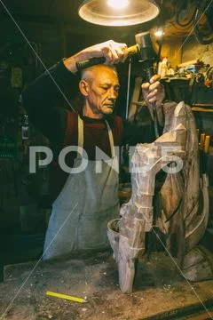 Master carpenter 50 - 55 years old creates wooden sculpture in the workshop Stock Photos