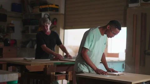 Master Carpenter and Apprentice Engaged in Woodwork at Carpentry Workshop. .. Stock Photos