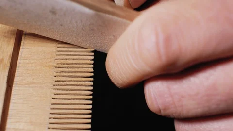 A master carpenter grinds a wooden comb manually with sanding paper close up. Stock Footage 105941102