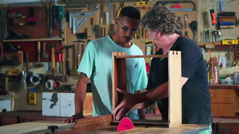 Master carpenter guiding apprentice at carpentry workshop, boss teaching st.. Stock Footage 247309909