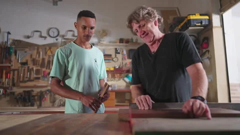 Master Carpenter Guiding Apprentice on Wood Sawing in Workshop, Young Appre.. Video stock 255870599