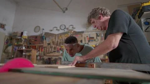 Master carpenter guiding student apprentice at carpentry workshop, job occu.. Foto stock