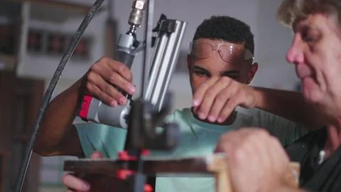 Master carpenter guiding young apprentice to build craftmanship furniture a.. Foto stock