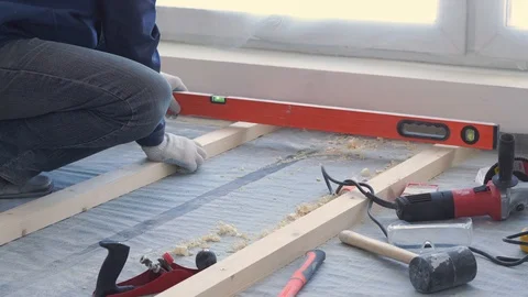 Master carpenter mounts pine wood floor - eco-friendly flooring. screwing lag to Stock Footage 107445771