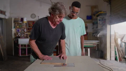 Master carpenter orienting apprentice to work with machine at woodworking c.. Video stock 246831601
