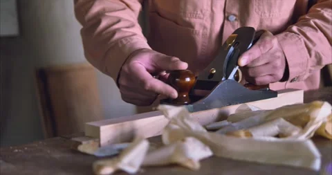 A master carpenter works with a small hand plane on wood with thin shavings Stock Footage 251944156