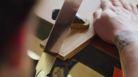 A master carves a dovetail joint on an oak board with a Japanese hand saw for Stock Footage 144244597