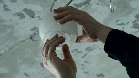 Master is changing the electric bulb in the chandelier. Stock Footage 169056963