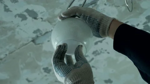 Master is changing the electric bulb in the chandelier. Stock Footage 170102561