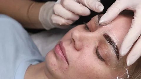 The master checks the newly applied pigment on the eyebrows. Stock Footage 165115563