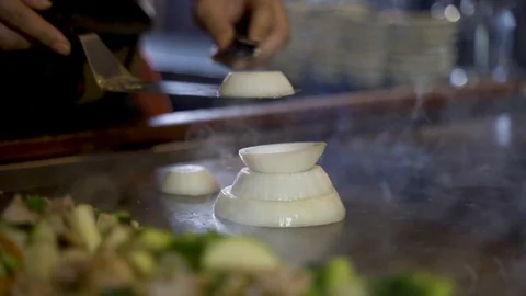 Master chef carefully builds an onion volcano on a steaming hot plate, Video stock 130165550