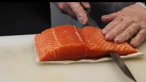 The master chef cuts salmon with a special knife ensuring each piece is uniform. Vidéo 284702011
