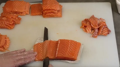 The master chef glides his knife through the salmon cutting it into smooth, even Stock Footage 284968049