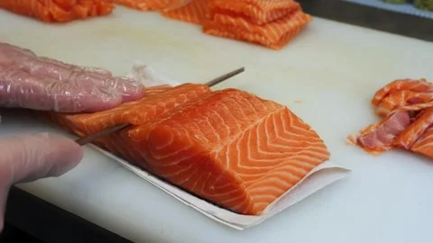 A master chef skillfully cuts fresh salmon into uniform pieces The gloved hands  Stock Footage 284703318