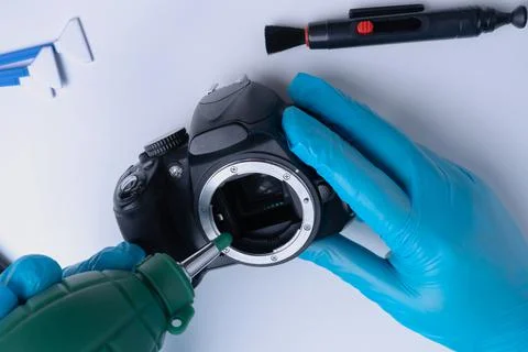Master cleans the DSLR camera sensor with a blower Stock Photos
