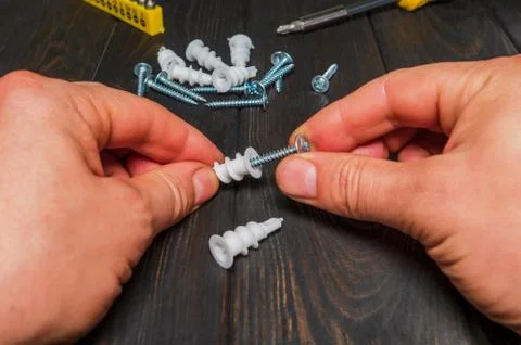 The master connects a screw with a plastic nozzle on black table Stock Photos
