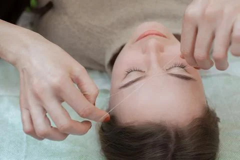 Master corrects makeup gives shape and thread plucks eyebrows Stock Photos