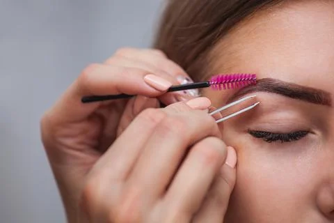 Master corrects makeup, plucks previously painted with henna eyebrows Stock Photos