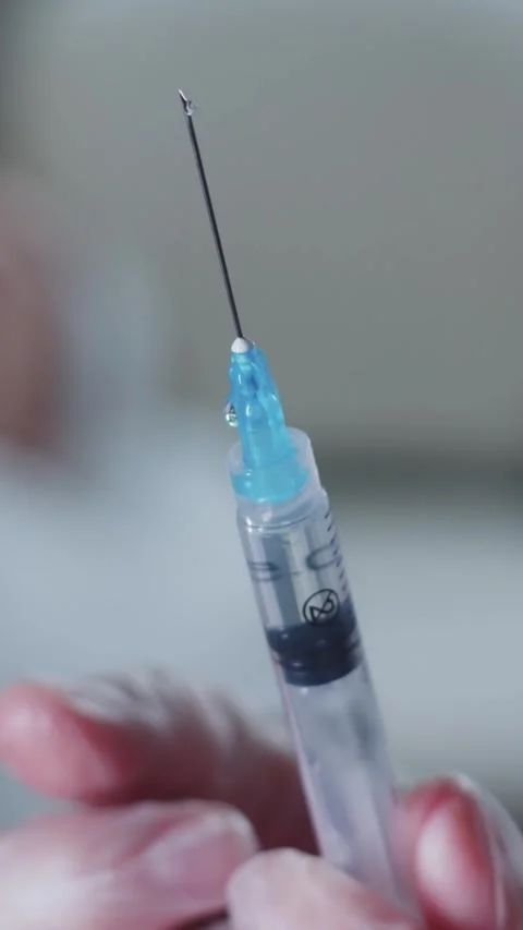 The master cosmetologist squeezes out excess air from the syringe and approaches Stock Footage 328444860