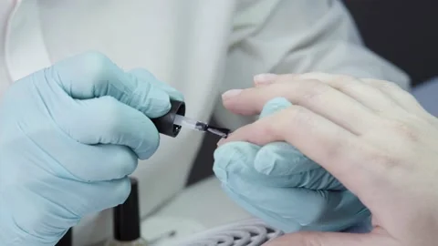 Master is covering the customer's nails with clear nail polish Stock Footage 194463891