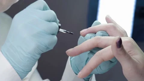 Master is covering the customer's nails with clear nail polish Stock Footage 194463919