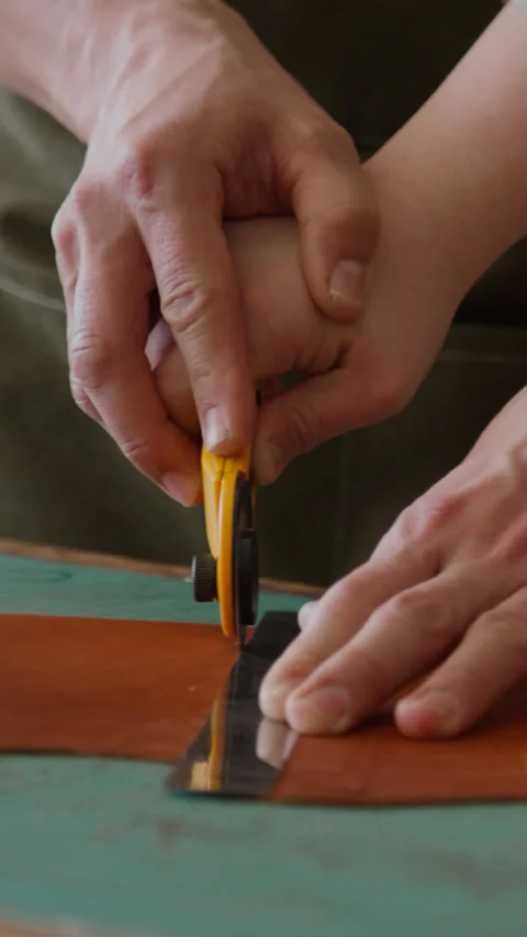 Master Craftsman Guiding Hand of his Apprentice, Cutting Brown Leather in Studio 스톡 동영상 301676431