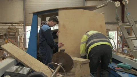Master craftsman shipwright and apprentice replace plywood bulkhead in boat Stock Footage 234178202