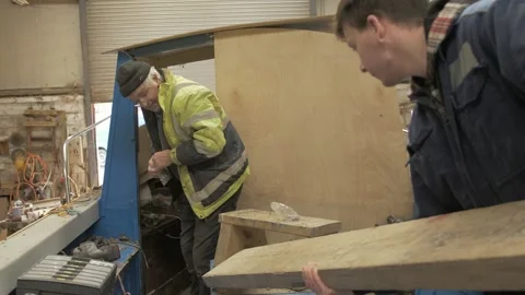 Master craftsman shipwright and apprentice work together repairing boat Stock Footage 234178494