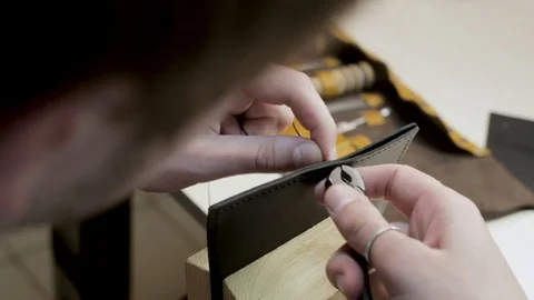 The master creates a leather wallet with his own hands with a needle, thread  Stock Footage