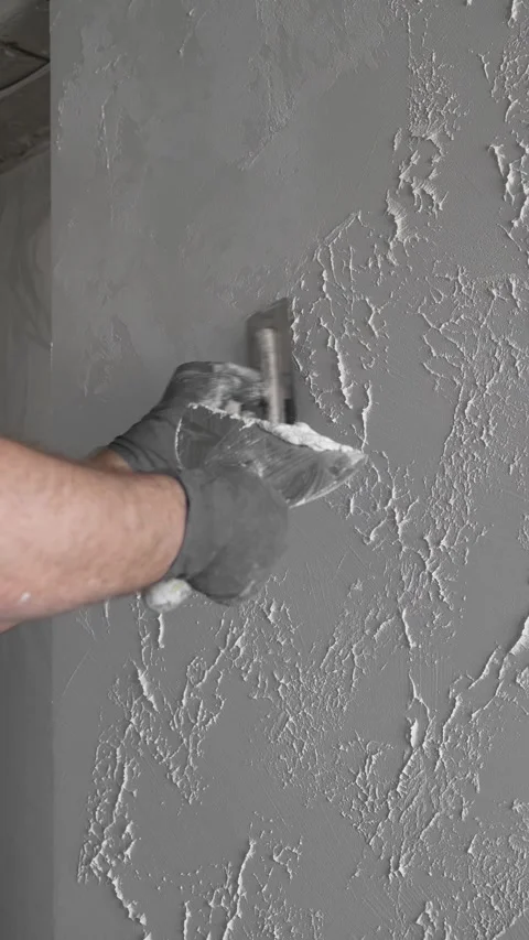 Master creates a pattern on decorative plaster with a spatula and trowel Video stock 317409544