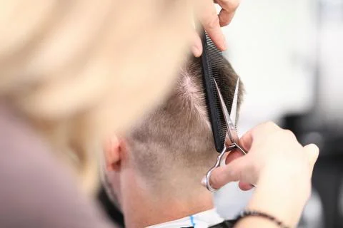 Master cuts man in the hands of scissors and comb. Stock Photos