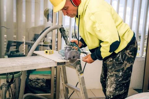 Master cuts the tile using an angle grinder with special diamond disc Stock Photos