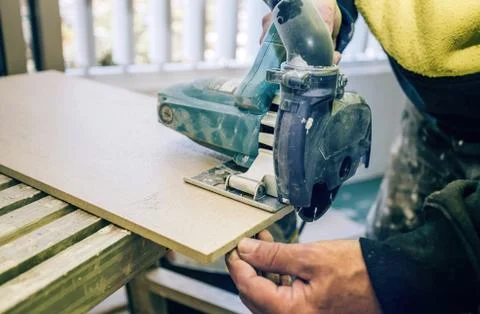 Master cuts the tile using an angle grinder with special diamond disc. Stock Photos