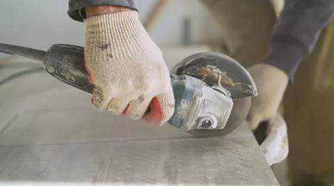 The master cuts the tiles on an angle grinder with a special diamond disc Stock Photos