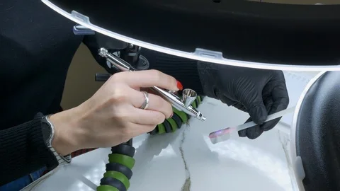 The master of design uses a spray gun to paint the stencil of a butterfly with Stock Footage 125404559