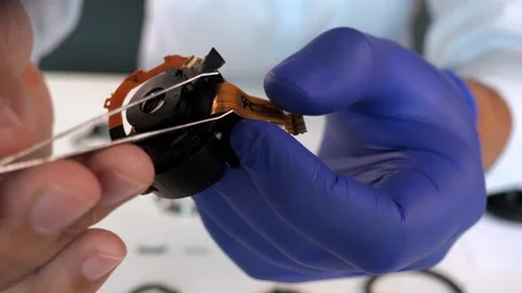 Master disassembling a camera lens and demonstrates the defect to the client Stock Footage 218464645