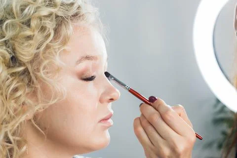 Master does a beautiful blonde makeup in a beauty salon Stock Photos