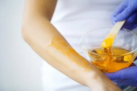 Master does epilation of hands with help of sugar paste hot wax in salon beauty. Stock Photos