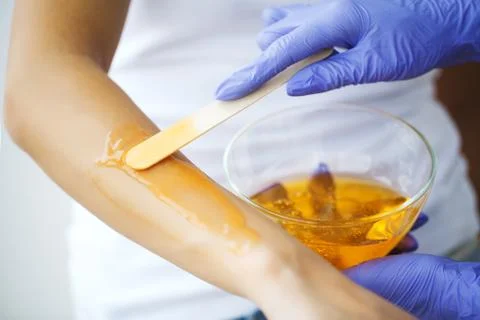 Master does epilation of hands with help of sugar paste hot wax in salon beauty. Stock Photos