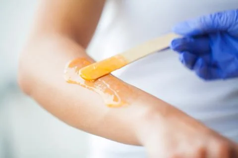 Master does epilation of hands with help of sugar paste hot wax in salon beauty Stock Photos