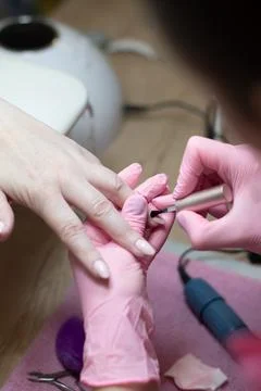 A master does a manicure to a client in a beauty salon and covers her nails Stock Photos
