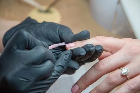 A master does a manicure to a client in a beauty salon and covers her nails Stock Photos