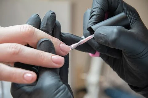 A master does a manicure to a client in a beauty salon and covers her nails Stock Photos