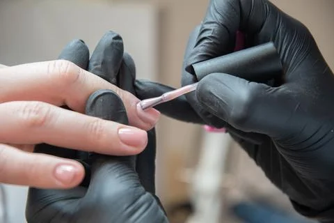 A master does a manicure to a client in a beauty salon and covers her nails Stock Photos