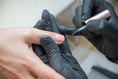 A master does a manicure to a client in a beauty salon and covers her nails Stock Photos