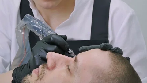 Master does tattoo of man's brows close-up Stock Footage 76686512