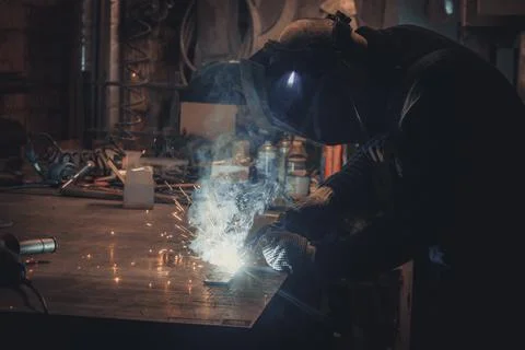 Master is doing welding at his workplace in the workshop, while sparks are .. Stock Photos