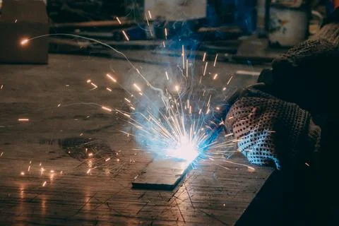 Master is doing welding at his workplace in the workshop, while sparks are .. Stock Photos