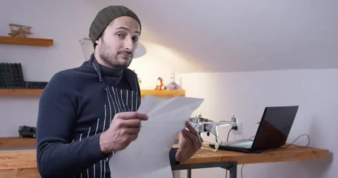A master with a drawing in his hands on the background of a laptop and a Stock Footage 147387874